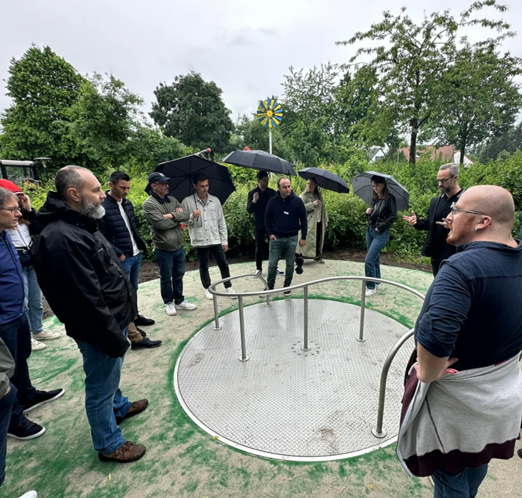 Employees of Kaiser and Kühne and the company Pro Urba form a standing circle around a play equipment 